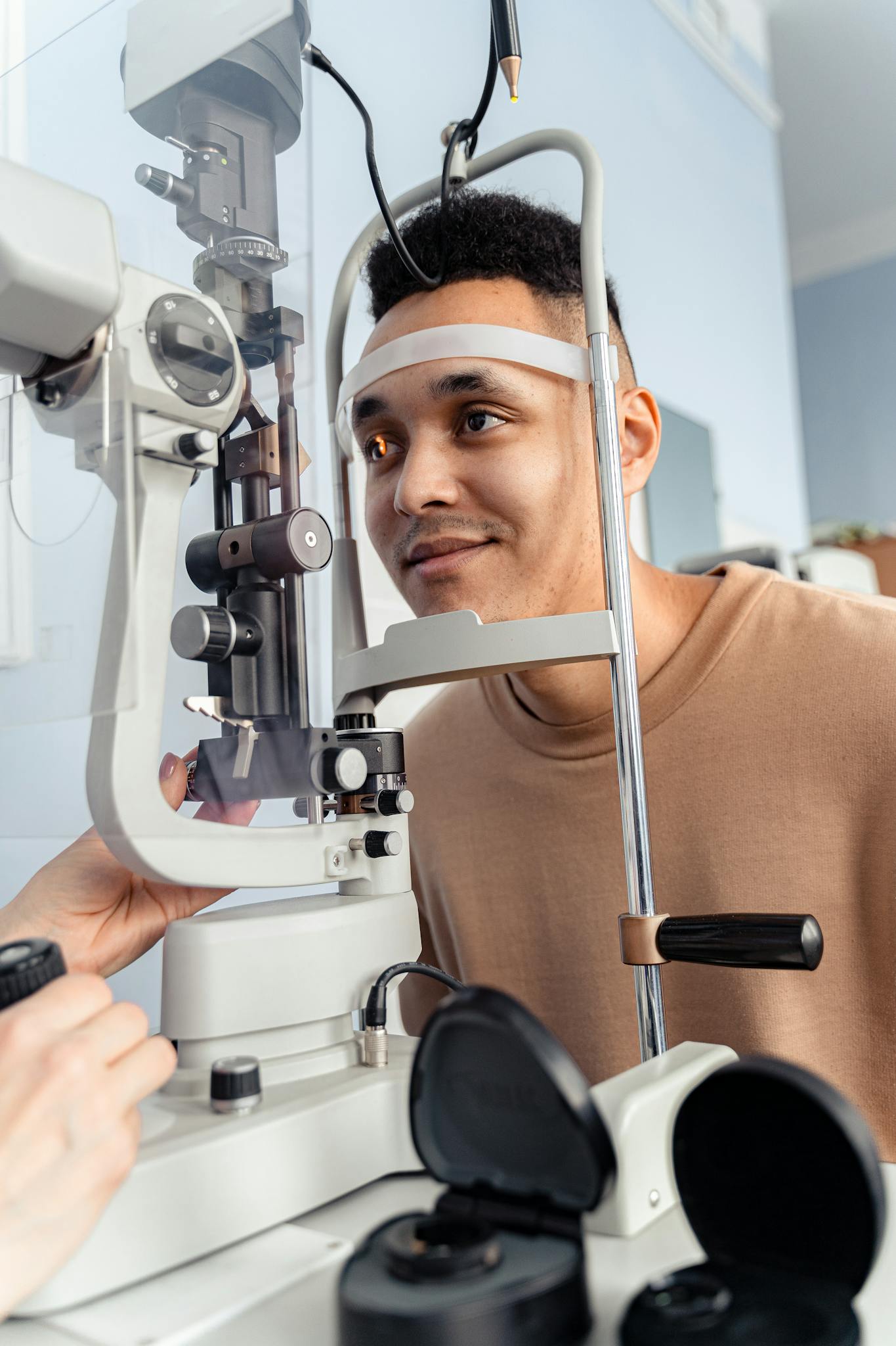 Adult man receiving an eye test with slit lamp in a clinic setting, showcasing efficient healthcare.
