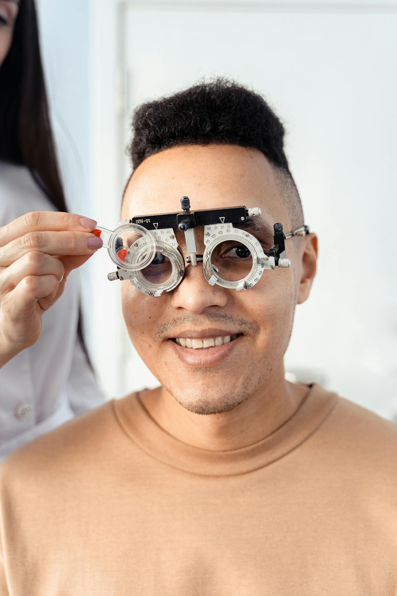Close-up of a smiling man having an eye exam with trial lens frames. Optometry setting.