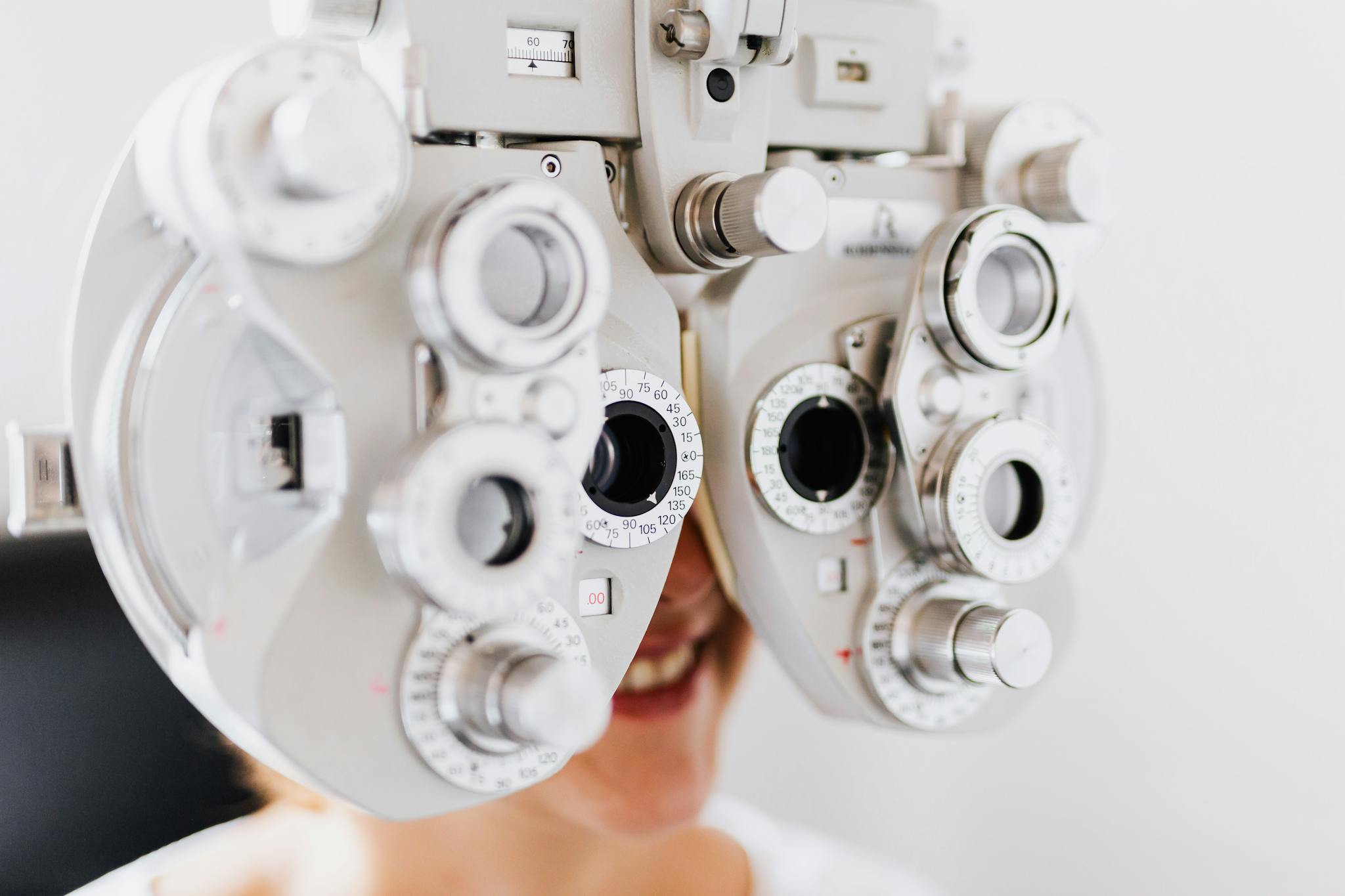 Close-up of woman undergoing an eye examination using a phoropter to test vision.