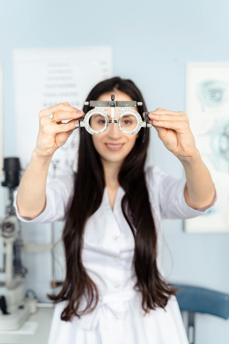 Smiling optometrist showing trial frames in a bright clinic setting.